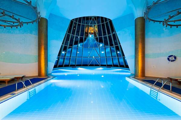 Innenpool des Blue Waters Club Hotels mit blauen Fliesen und Glasdach.