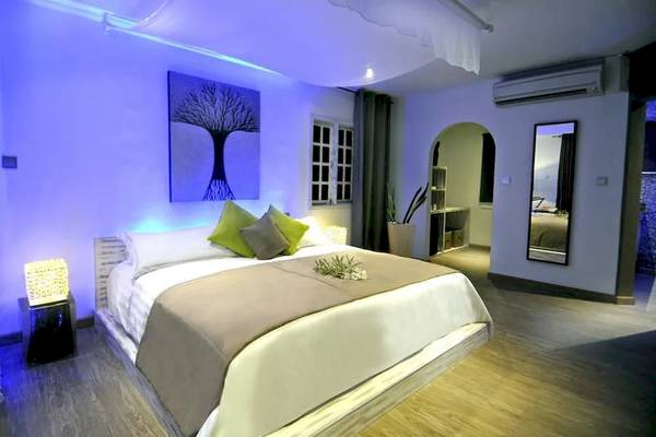 Schlafzimmer im Le Domaine de L'Orangeraie Resort & Spa mit violetten Beleuchtung und einem großen Bett.