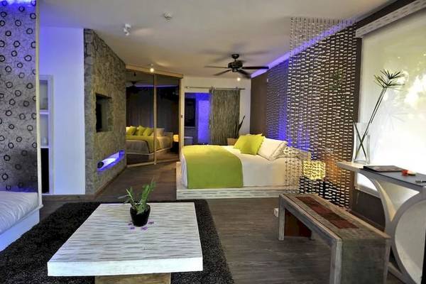 Innenansicht eines Hotelzimmers von Le Domaine de L'Orangeraie Resort & Spa mit einem Bett, grüner Bettwäsche und einer modernen Einrichtung.
