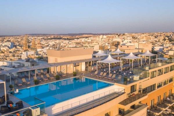 Dachterrasse des AX The Palace Hotels mit Swimmingpool und Sonnenliegen.