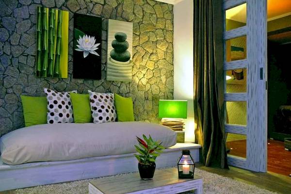 Zimmer im Le Domaine de L'Orangeraie Resort & Spa mit Steinwand, grünen Kissen und Pflanzen