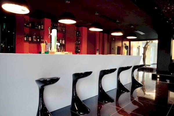 Barbereich im Ushuaia Ibiza Beach Hotel mit schwarzen Stühlen und roten Wänden.