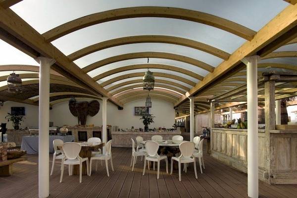 Terrasse des Ushuaia Ibiza Beach Hotels mit Holzmöbeln und einer Dachkonstruktion.