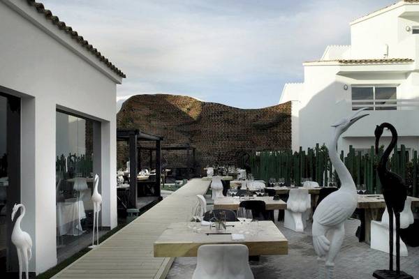 Außenbereich des Ushuaia Ibiza Beach Hotel mit Tischen, Stühlen und weißen Skulpturen.