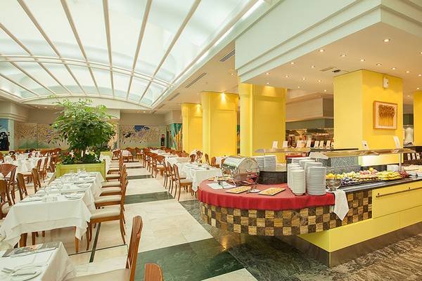 Buffetbereich im Lopesan Costa Meloneras Resort & Spa mit gelben Säulen und einem zentralen Tisch voller Speisen.