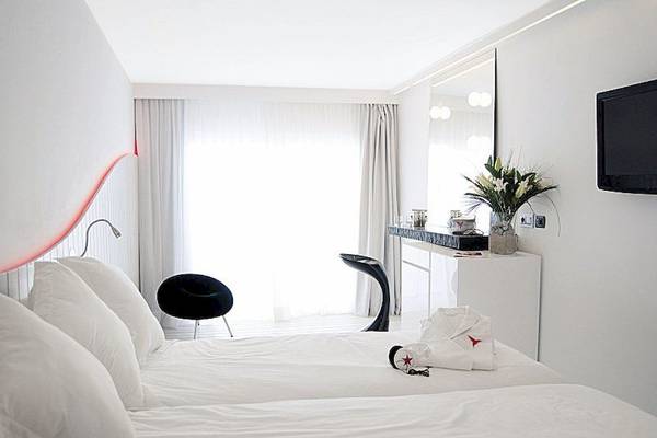 Innenansicht eines Doppelzimmers im Ushuaia Ibiza Beach Hotel mit weißen Möbeln und Accessoires.