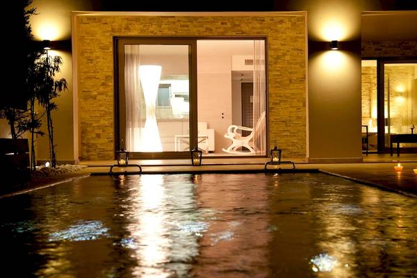 Pool bei Nacht im Sentido Port Royal Villas & Spa mit illuminierten Gebäuden und Kerzen.