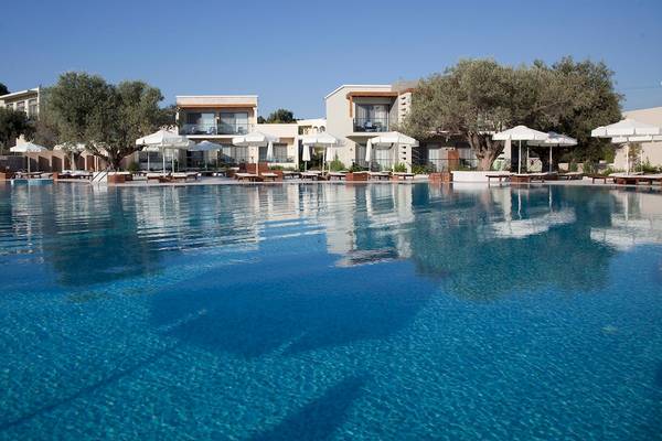 Außenpool des Sentido Port Royal Villas & Spa Hotels mit Sonnenliegen und weißen Sonnenschirmen.
