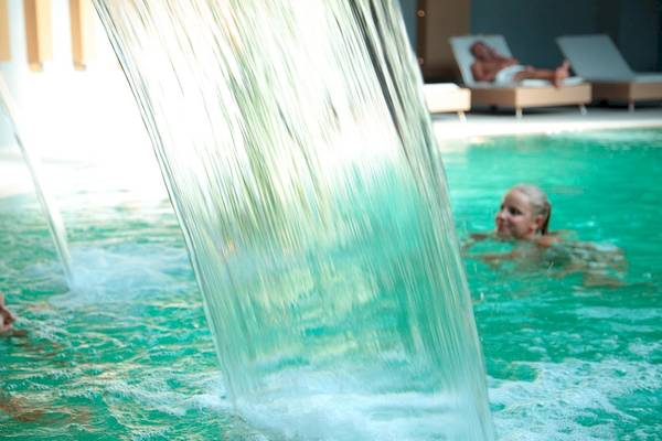 Gäste im innenpool unter einem großen wasserfall im sentido port royal villas & spa