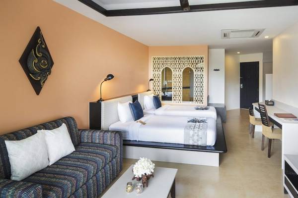 Hotelzimmer im Anyavee Tubkaek Beach Resort mit zwei Betten, Sofa, Fernseher und Schreibtisch.
