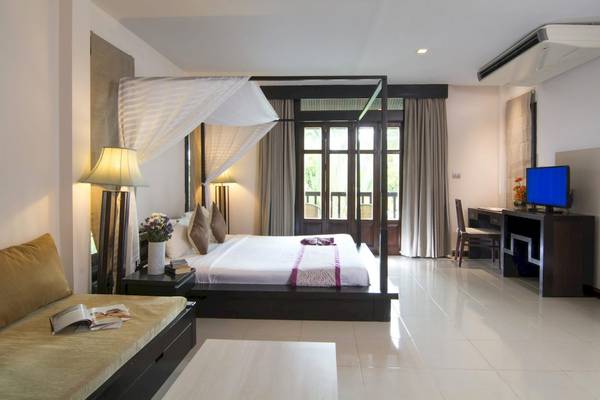 Schlafzimmer im Anyavee Tubkaek Beach Resort mit Himmelbett, Fernseher, Schreibtisch und Balkon.