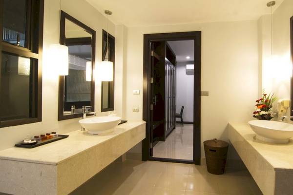 Badezimmer im Anyavee Tubkaek Beach Resort mit zwei Waschbecken, Spiegeln und einem Blumenstrauß.