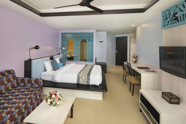 Hotelzimmer im Anyavee Tubkaek Beach Resort mit Bett, Sofa, Tisch und Fernseher.