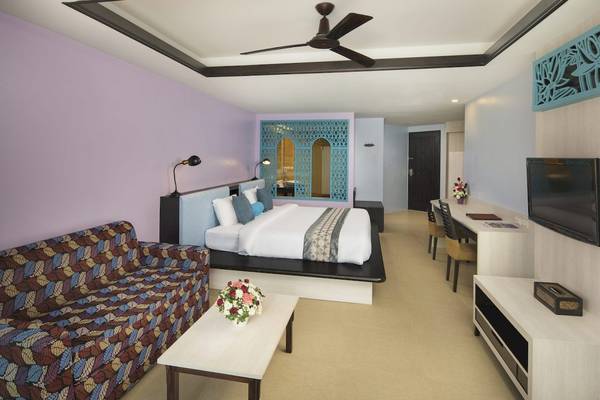 Zimmer im Anyavee Tubkaek Beach Resort mit Bett, Sofa, Tisch und Fernseher.