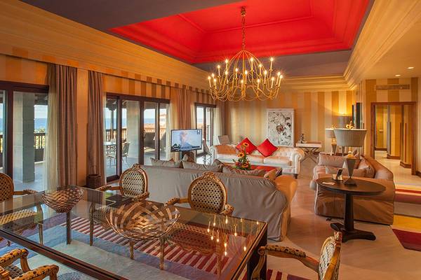 Wohnbereich des Lopesan Costa Meloneras Resort & Spa mit Meerblick, Kronleuchter, Sofas, Tischen und Fernseher.