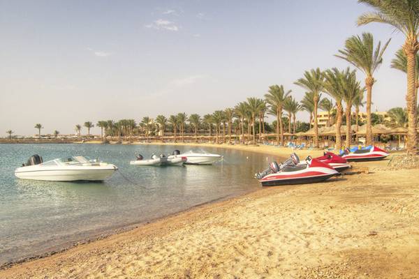 Strand des Continental Hotel Hurghada mit mehreren geparkten Booten und Palmen