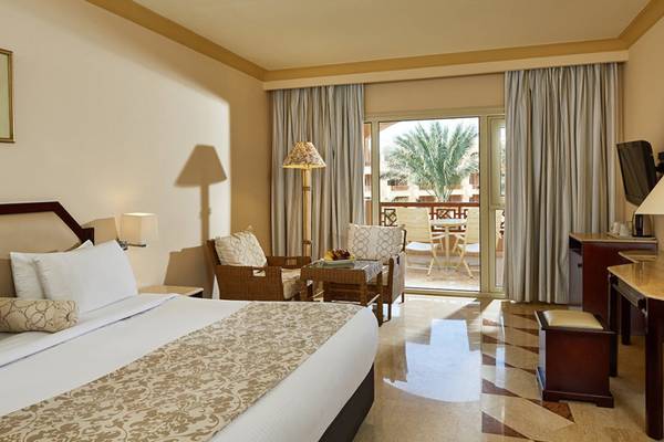 Luxuriöses Hotelzimmer im Continental Hotel Hurghada mit Balkon, bequemen Möbeln und Blick auf Palmen.