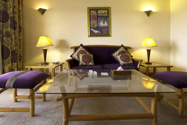 Wohnbereich im Continental Hotel Hurghada mit einem Glastisch, einem Sofa, Kissen, zwei Nachttischen und Lampen.