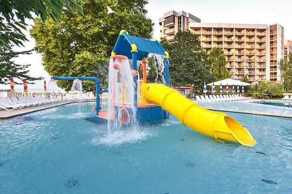 Wasserrutsche im Außenbereich des Kaliakra Beach Hotels mit grünen Bäumen und Gebäude im Hintergrund.