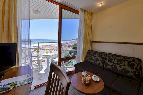 Hotelzimmer mit Meerblick im Kaliakra Beach Hotel, mit Sofa, Tisch, Fernseher und Balkon.