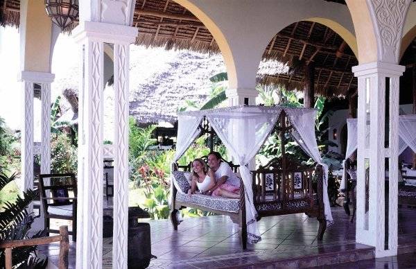 Ein Paar sitzt auf einem Bett im VOI Kiwengwa Resort.