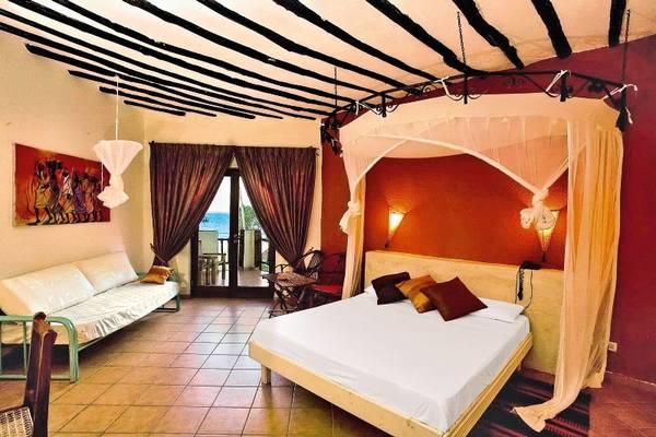 Schlafzimmer im VOI Kiwengwa Resort mit Bett, Couch und Balkonzugang.