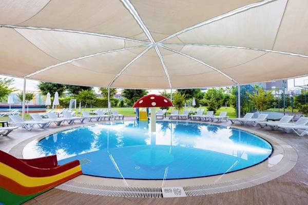 Außenpoolbereich des Calimera Hane Garden Hotels mit schattenspendenden Schirmen und buntem Wasserrutsche.
