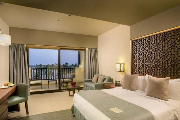 Schlafzimmer im Fanar Hotel & Residences mit einem großen Bett, Balkon und Meerblick.