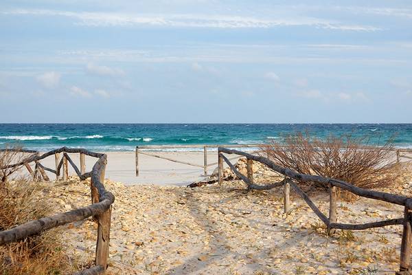 Strand mit Wellen und einem Holzzaun am Horizont