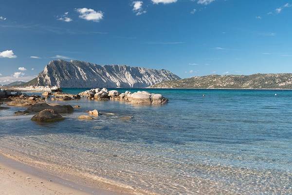 Strand mit Felsen und Blick auf das Meer und eine Bergkette.