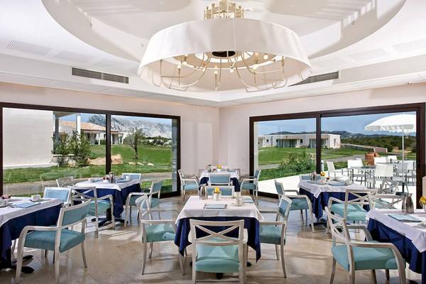 Innenansicht des Restaurants im Grande Baia Resort & Spa mit großen Fenstern und Blick auf die Landschaft.