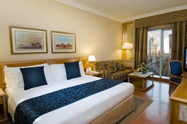 Hotelzimmer im Millennium Plaza Downtown mit Bett, Sofa, Fernseher und Stadtblick.