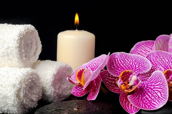 Spa-Einrichtung mit Kerze, Orchideen, Handtüchern und Steinen im Millennium Plaza Downtown Hotel