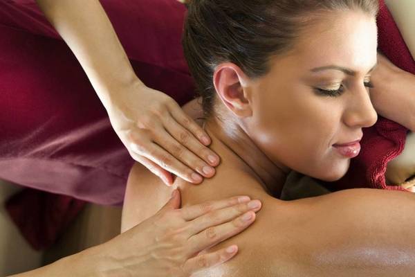 Frau erhält Schultermassage im Hotel, während sie entspannt auf dem Rücken liegt.