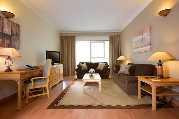 Wohnzimmer im Millennium Plaza Downtown Hotel mit zwei Sofas, Tisch, Fernseher und Lampen.