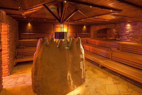 Innenansicht der Sauna im Lopesan Costa Meloneras Resort & Spa mit Holzbänken und einer großen Sandsteinskulptur.
