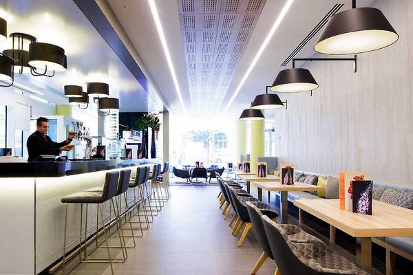 Barbereich im Novotel London Blackfriars mit Barkeeper, Stühlen und Tischen.