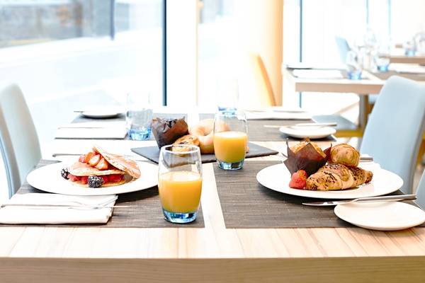 Frühstückstisch im Novotel London Blackfriars mit Pfannkuchen, Croissants, Brötchen und Orangensaft.