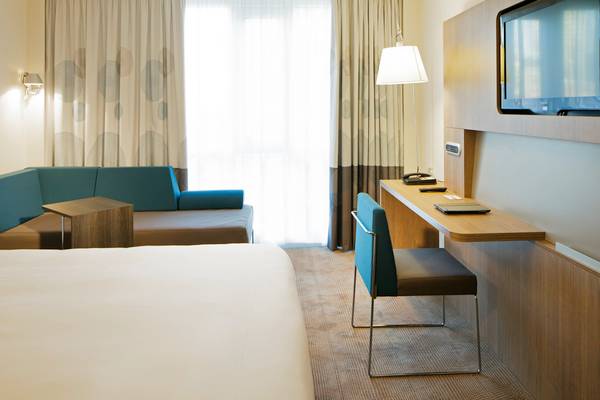 Hotelzimmer im Novotel London Blackfriars mit Bett, Schreibtisch, Stuhl und Sofa.