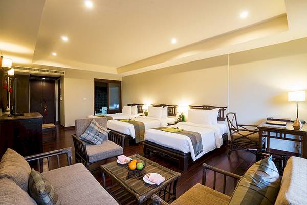 Hotelsuite im Khao Lak Laguna Resort mit zwei Betten, Möbeln und Früchten auf dem Tisch.