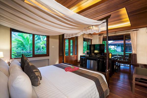Ein Schlafzimmer mit einem Bett, Fernseher und Aussicht auf den Garten im Khao Lak Laguna Resort.