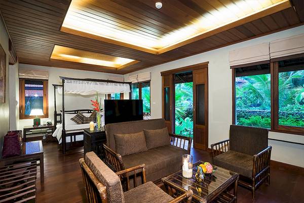 Wohnbereich des Khao Lak Laguna Resorts mit Bett, Sofa und Fenstern mit Blick auf den Garten.