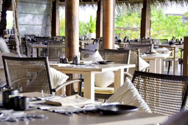 Außenrestaurant des Anantara Dhigu Maldives Resorts mit gedeckten Tischen und Stühlen.