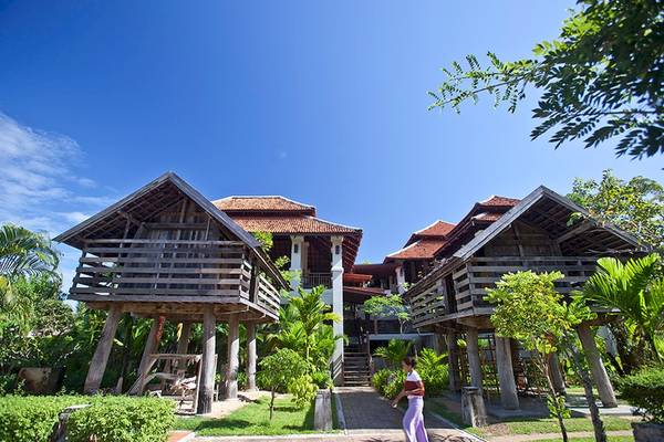 Foto von drei Holzhäusern im Khao Lak Laguna Resort, umgeben von Grün.