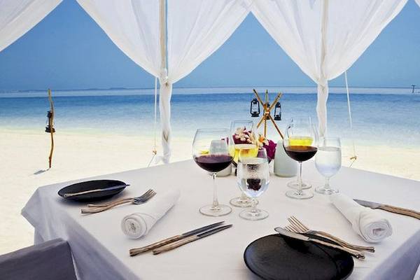 Anantara Dhigu Maldives Resort Strandtisch mit Getränken und Essensteller.