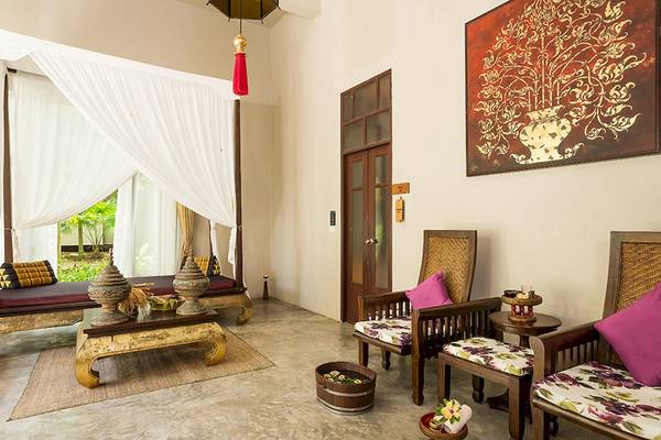 Innenraum des Khao Lak Laguna Resorts mit einem Bett, Sesseln und einem Tisch.