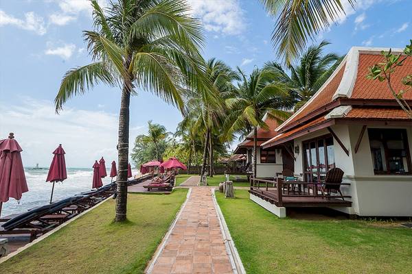 Außenansicht des Khao Lak Laguna Resorts mit Strand, Sonnenliegen und Palmen.