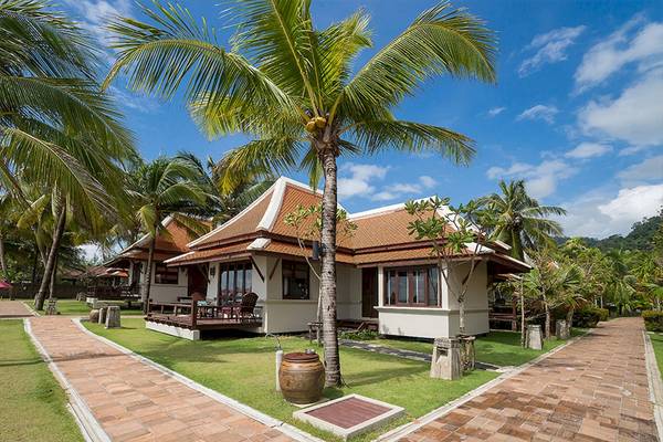 Villas des Khao Lak Laguna Resorts vor der Kulisse von Palmen und blauem Himmel.
