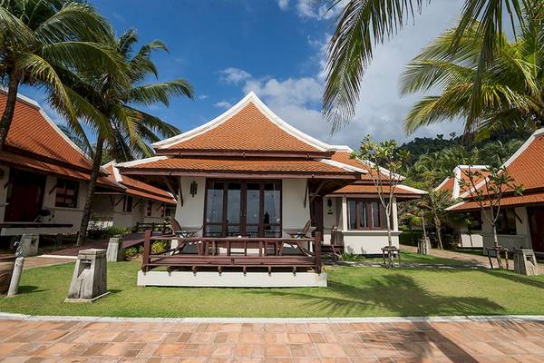 Außenansicht der Khao Lak Laguna Resort Villas mit roten Dächern und einem gepflegten Rasen vor den Gebäuden.