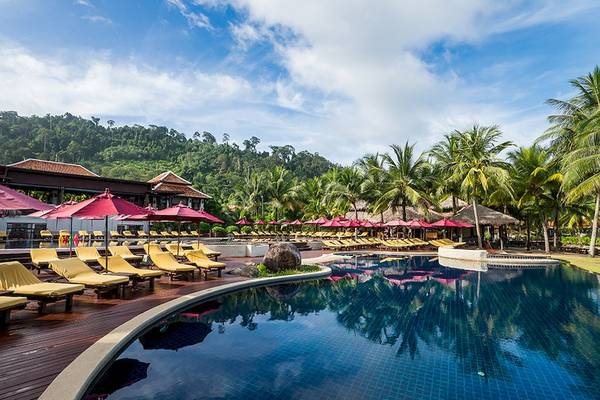 Poolbereich des Khao Lak Laguna Resorts mit gelben Sonnenliegen und roten Sonnenschirmen.